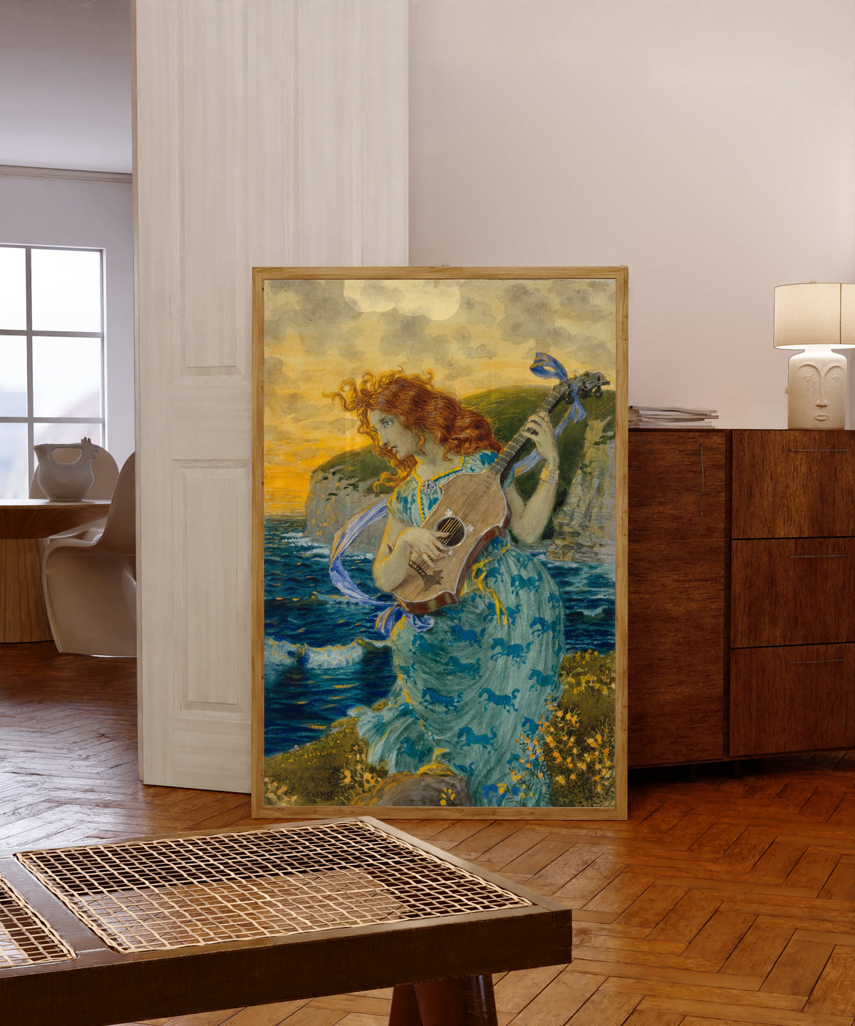 Framed art print of Die Tochter des Barden by Eugène Grasset, in a light wood frame leaning in a warm room with a parquet floor