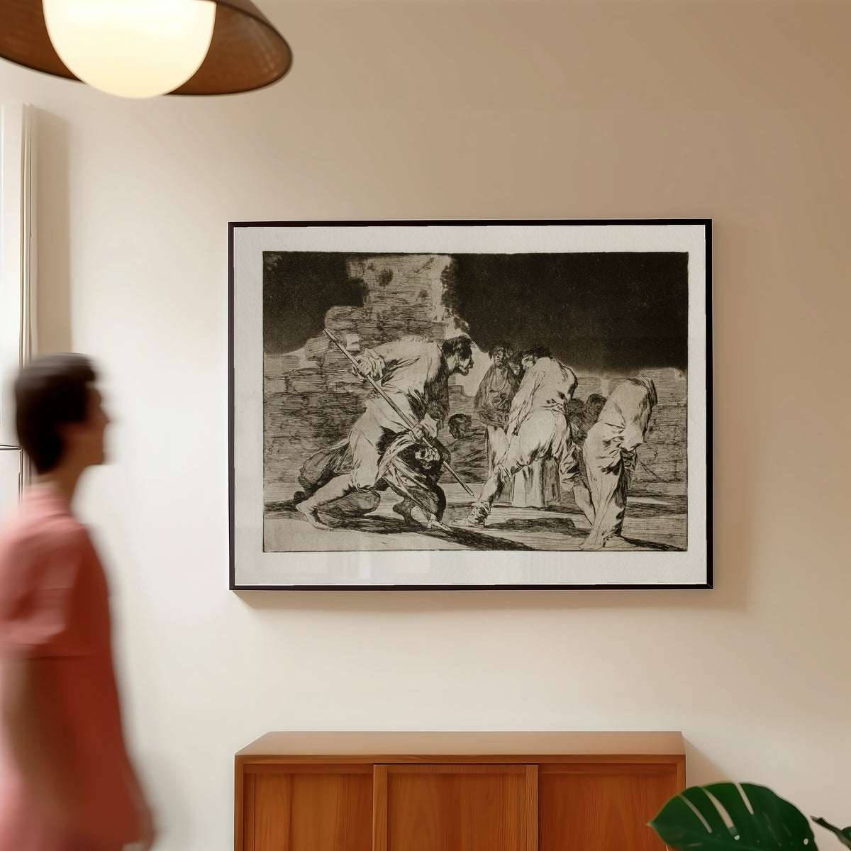 Framed art print of Disparate cruel (Cruel Folly), from Los Disparates by Francisco de Goya, in a slim black frame on a warm wall in a sunlit room