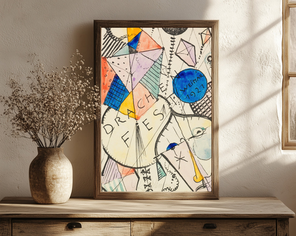 Framed art print of Drachenfest by Oskar Schlemmer, in a dark wood frame leaning on a rustic console beside dried flowers