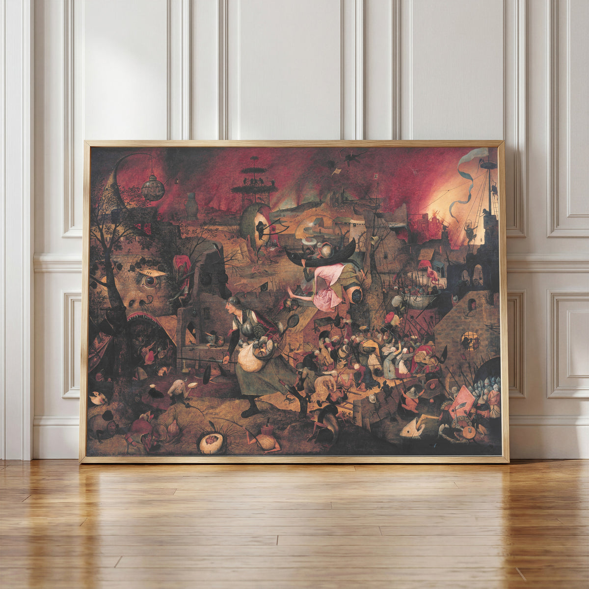 Framed art print of Dulle Griet by Pieter Bruegel the Elder, in a light wood frame leaning against a panelled white wall