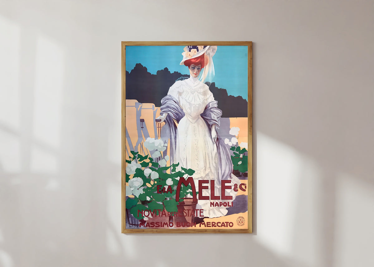 Framed art print of E. & A. Mele, Napoli: Novità per l'Estate, Massimo Buon Mercato by Leopoldo Metlicovitz, in a light wood frame on a sunlit white wall