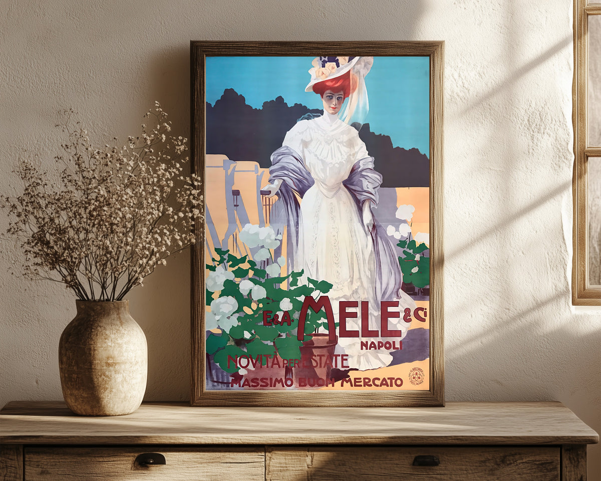 Framed art print of E. & A. Mele, Napoli: Novità per l'Estate… by Leopoldo Metlicovitz, in a dark wood frame leaning on a rustic console beside dried flowers