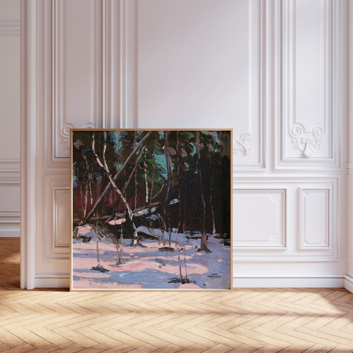 Framed art print of Early Snow, Algonquin Park by Tom Thomson, leaning against pale pink panelling on a herringbone floor