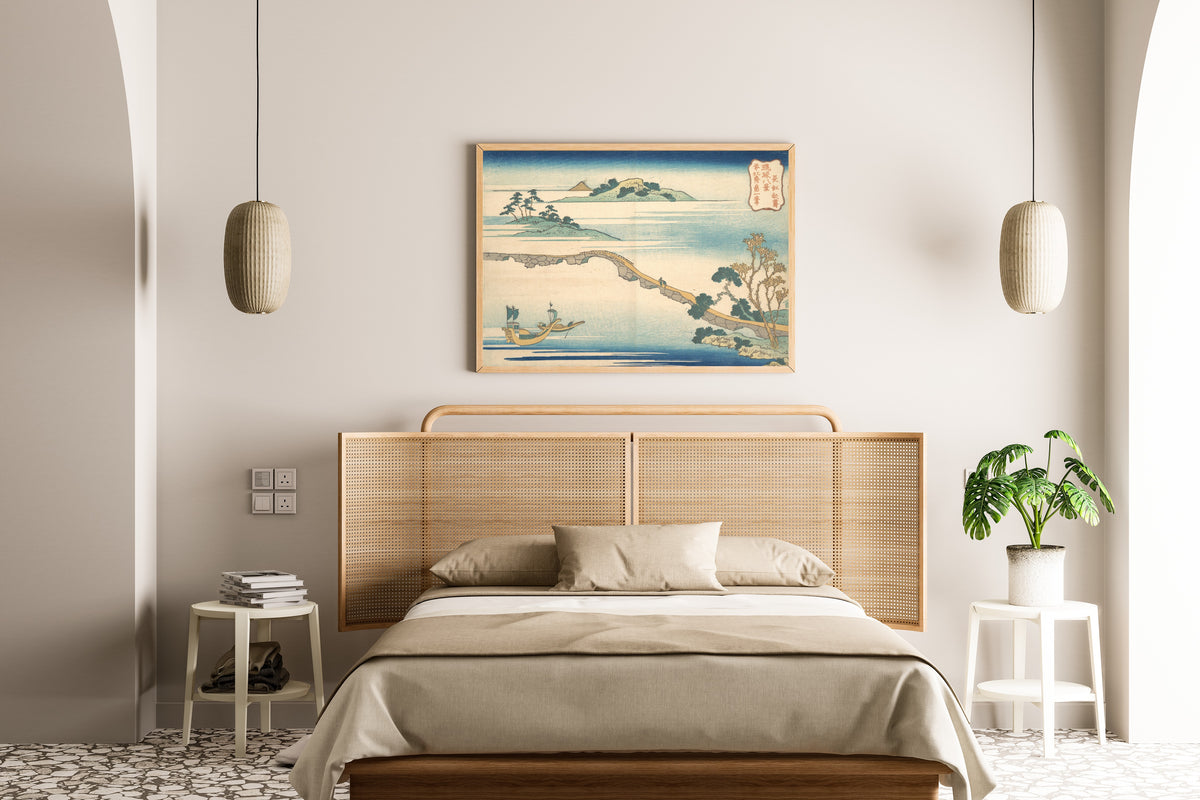 Framed art print of Eight Views of the Ryūkyū Islands: Autumn Sky at Chōkō by Katsushika Hokusai, above a cane-headboard bed
