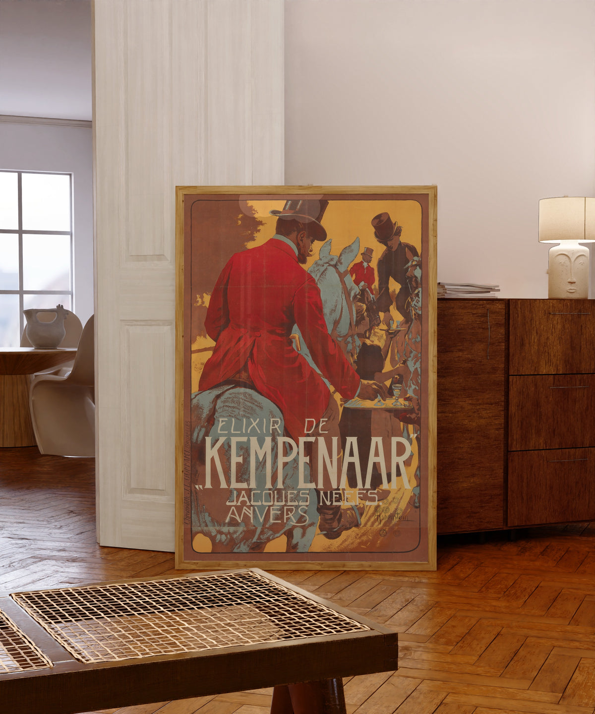 Framed art print of Elixir de Kempenaar by Adolfo Hohenstein, in a light wood frame leaning in a warm room with a parquet floor