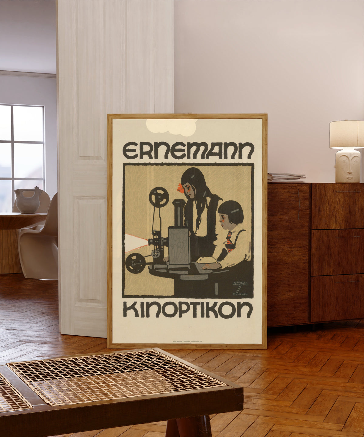 Framed art print of Ernemann Kinoptikon by Ludwig Hohlwein, in a light wood frame leaning in a warm room with a parquet floor