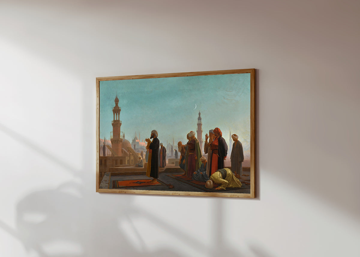 Framed art print of Evening Prayer, Cairo by Jean-Léon Gérôme, in a light wood frame on a sunlit white wall, seen at a slight angle