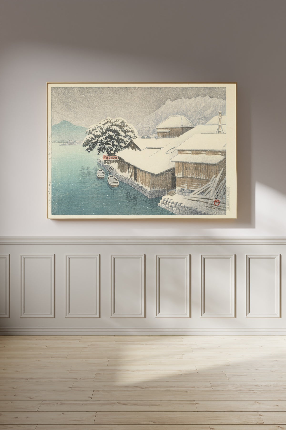 Framed art print of Evening Snow at Ishinomaki by Kawase Hasui, on a panelled wall in afternoon light