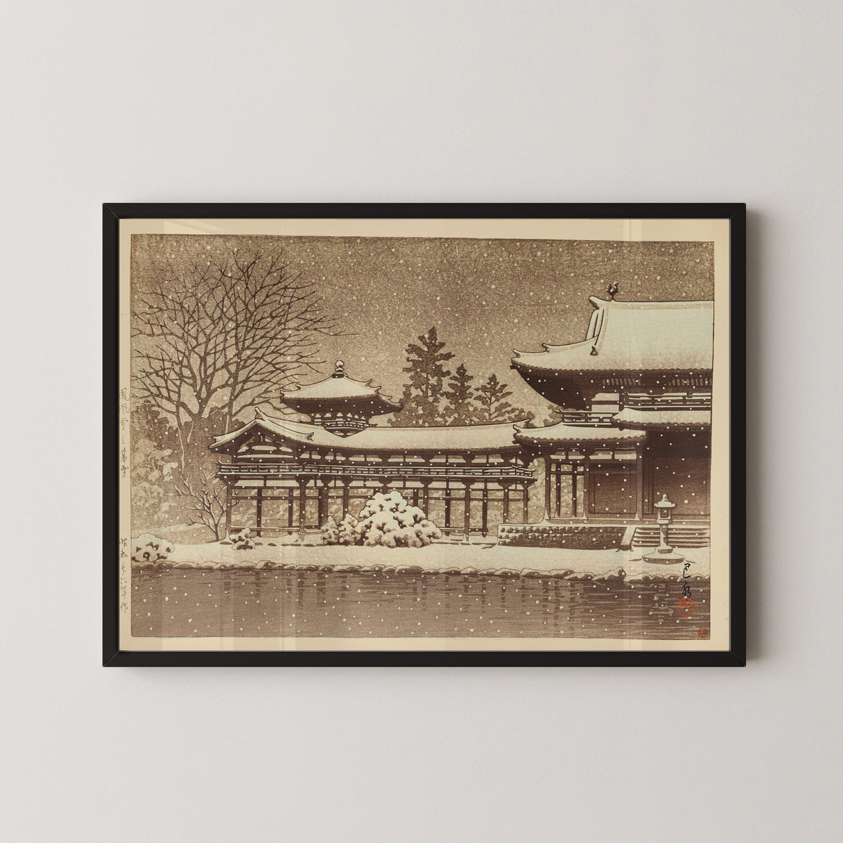 Framed art print of Evening Snow at Phoenix Hall by Kawase Hasui, in a black frame on a pale wall