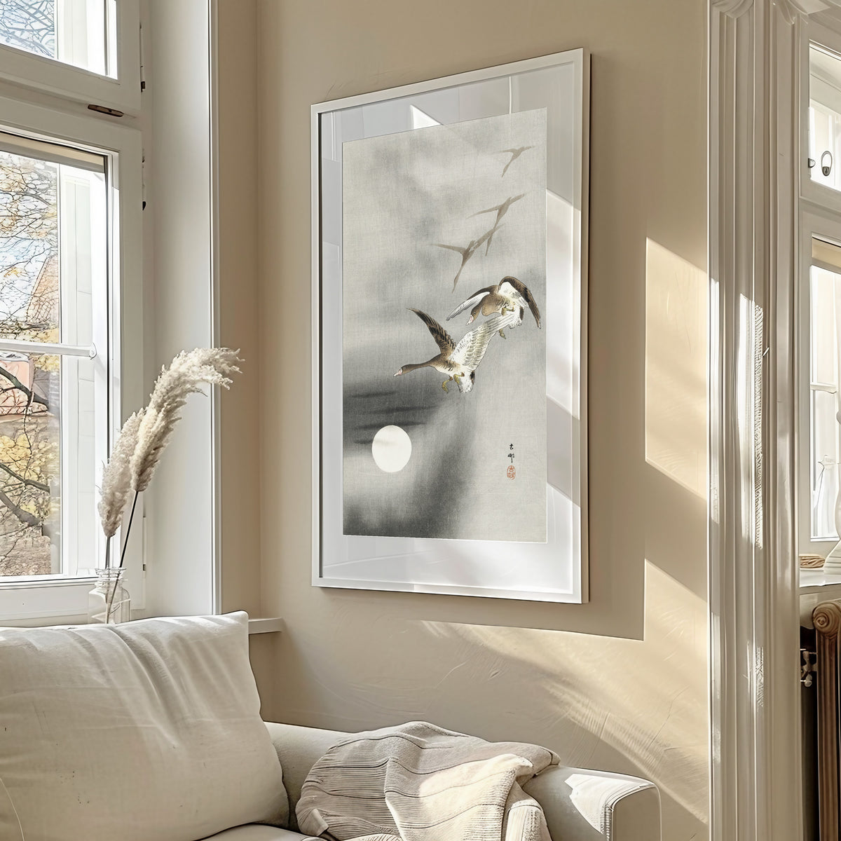 Framed art print of Five Geese in Flight at Full Moon by Ohara Koson, in a sunlit living room above a sofa