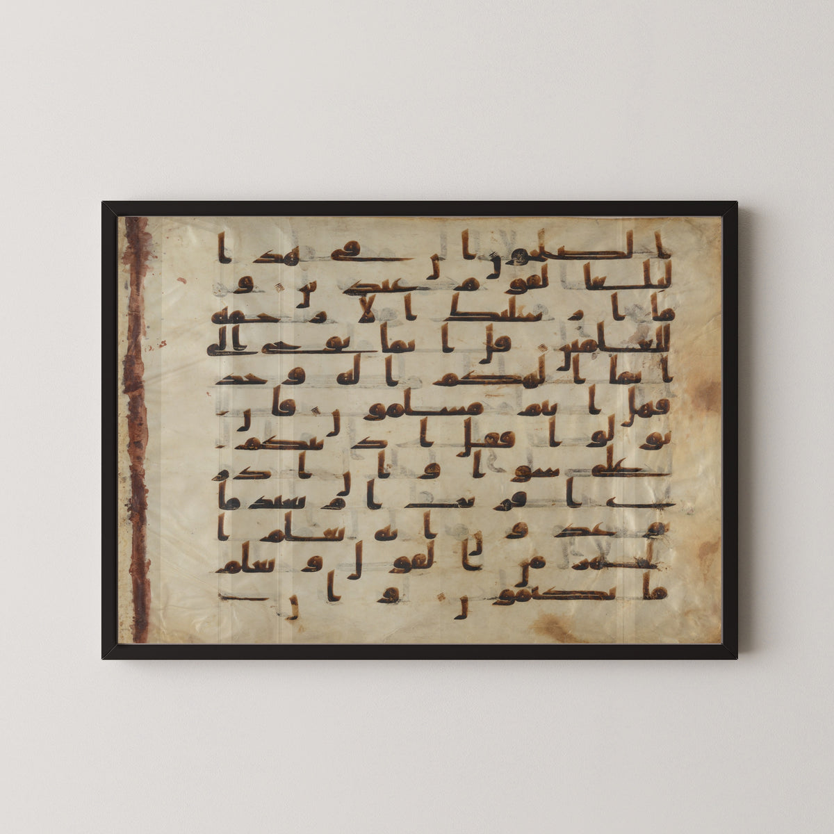 Framed art print of Folio from the Tashkent Qur'an, in a black frame on a pale wall