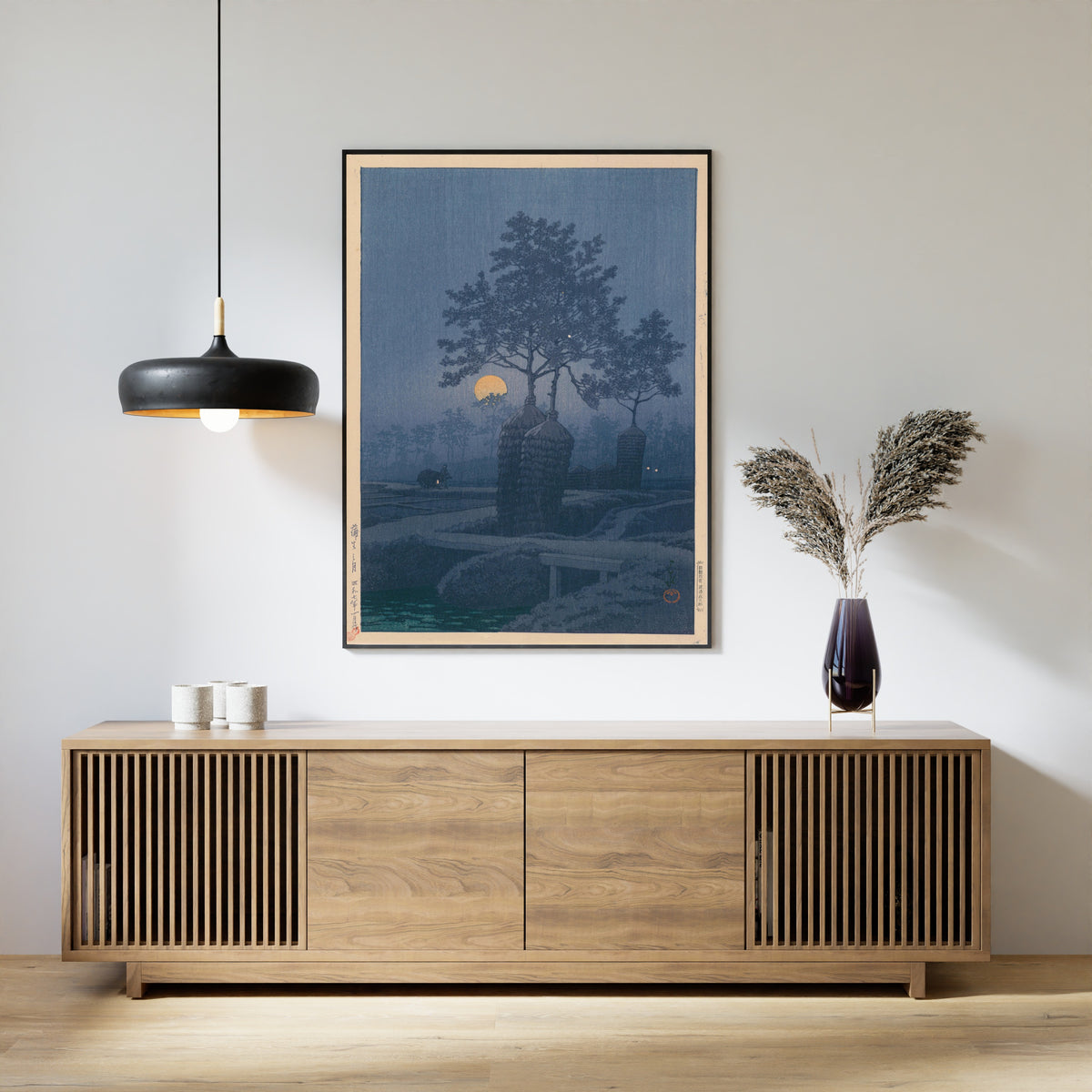 Framed art print of Full Moon at Gamo by Kawase Hasui, above a slatted wood sideboard