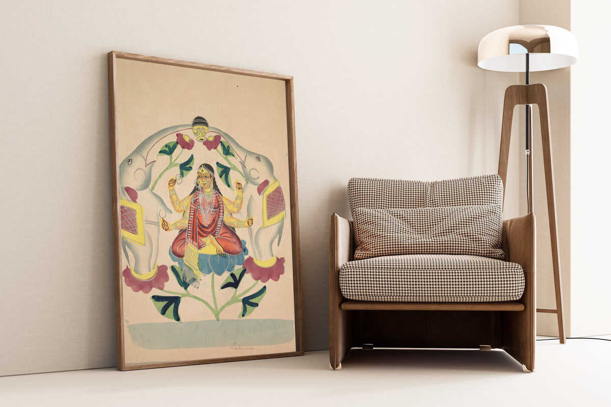 Framed art print of Gajalakshmi: Lakshmi with Elephants by Kalighat painter, leaning against a wall beside an armchair and a floor lamp