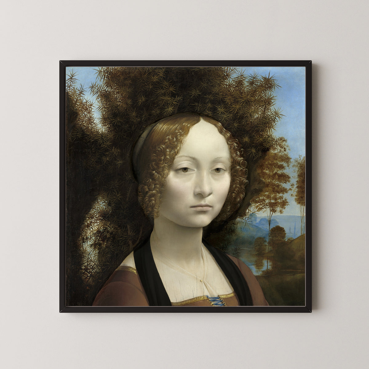 Framed art print of Ginevra de’ Benci by Leonardo da Vinci, in a black frame on a pale wall
