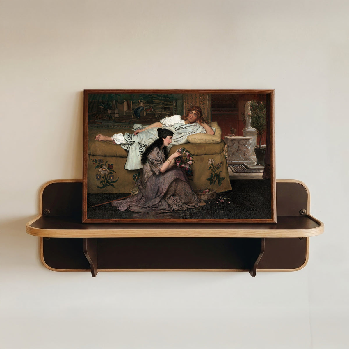 Framed art print of Glaucus and Nydia by Lawrence Alma-Tadema, in a dark wood frame resting on a wall shelf