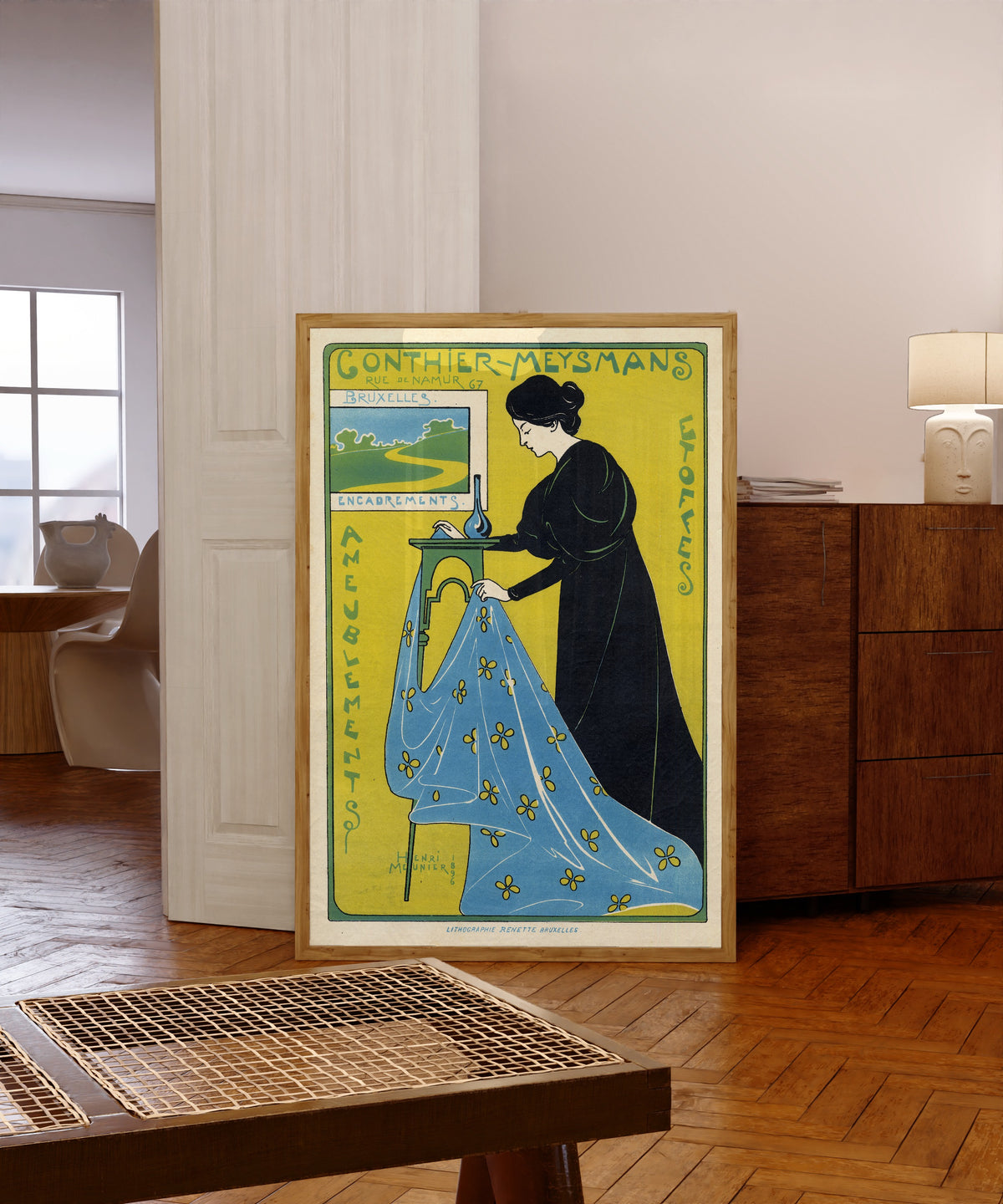 Framed art print of Gonthier-Meysmans, Rue de Namur 67, Bruxelles by Henri Meunier, in a light wood frame leaning in a warm room with a parquet floor