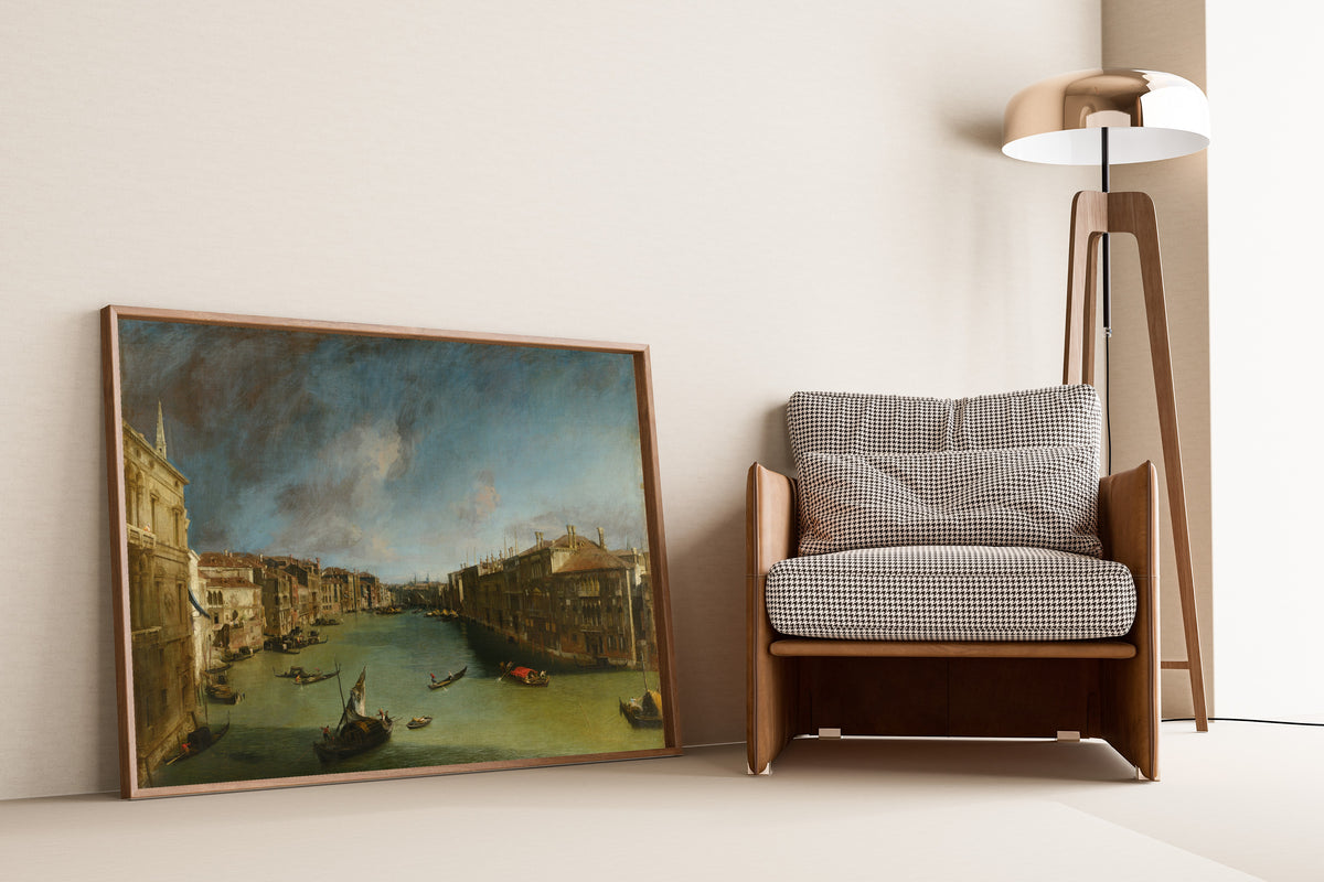 Framed art print of Grand Canal from Palazzo Balbi towards the Rialto by Canaletto, leaning against a wall beside an armchair and a floor lamp
