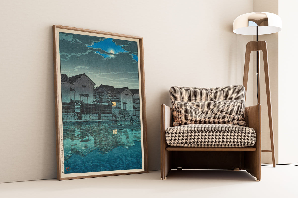 Framed art print of Hazy Moon at Matsue in Izumo by Kawase Hasui, leaning against a wall beside an armchair and a floor lamp