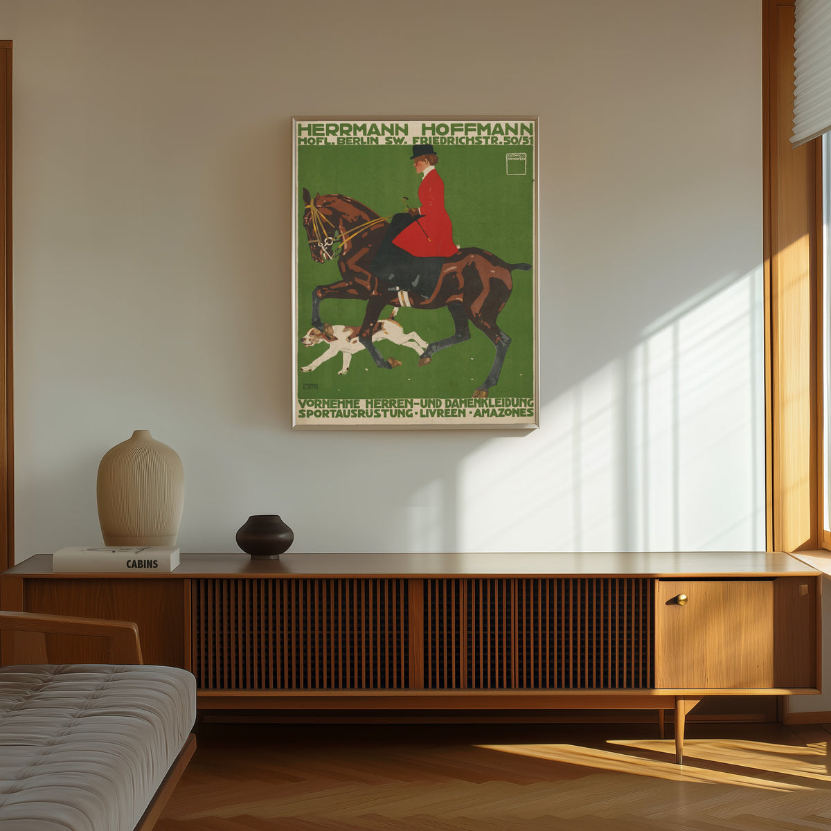 Framed art print of Herrmann Hoffmann: Vornehme Herren- und Damenkleidung by Ludwig Hohlwein, in a thin light frame on a sunlit wall above a wooden sideboard