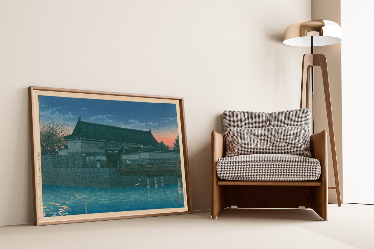 Framed art print of Hirakawa Gate by Kawase Hasui, leaning against a wall beside an armchair and a floor lamp