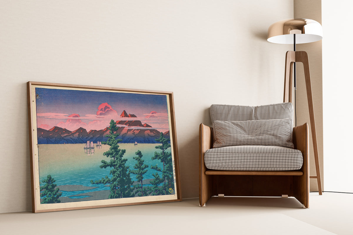 Framed art print of Hizen, Mount Unzen by Kawase Hasui, leaning against a wall beside an armchair and a floor lamp