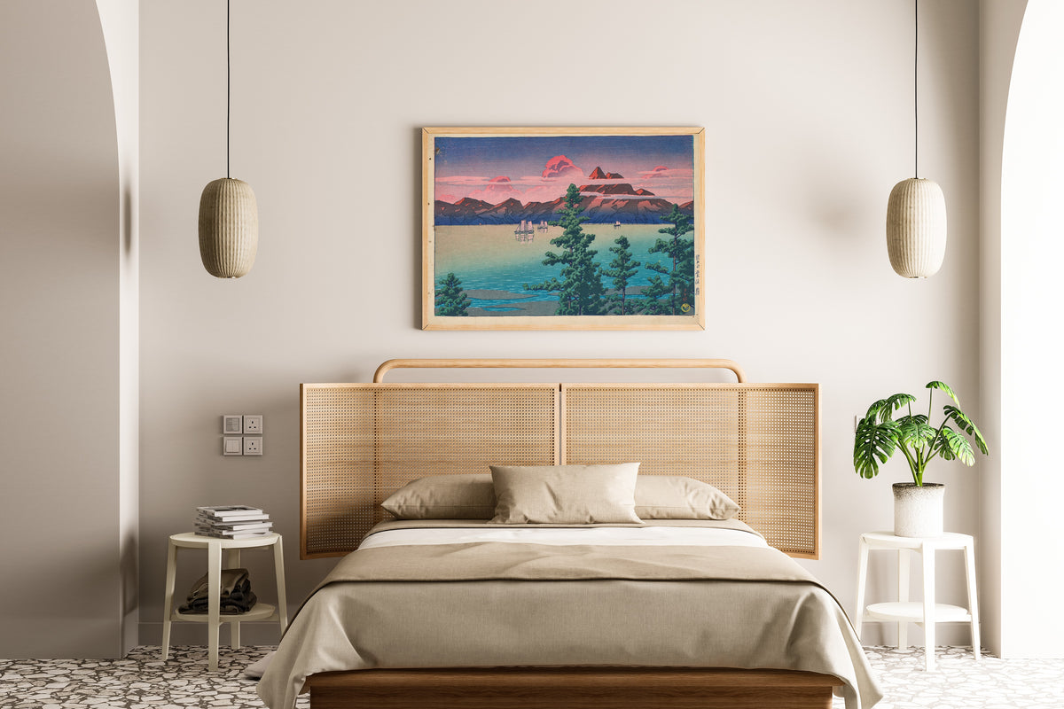 Framed art print of Hizen, Mount Unzen by Kawase Hasui, above a cane-headboard bed