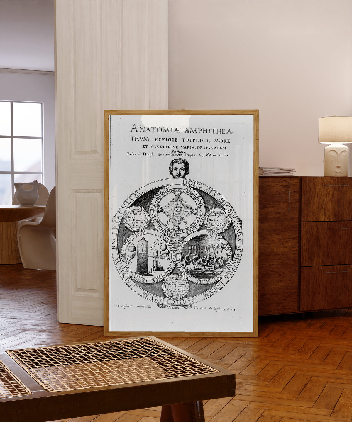 Framed art print of Homo seu Microcosmus: Title Plate of Anatomiae… by Robert Fludd, in a light wood frame leaning in a warm room with a parquet floor