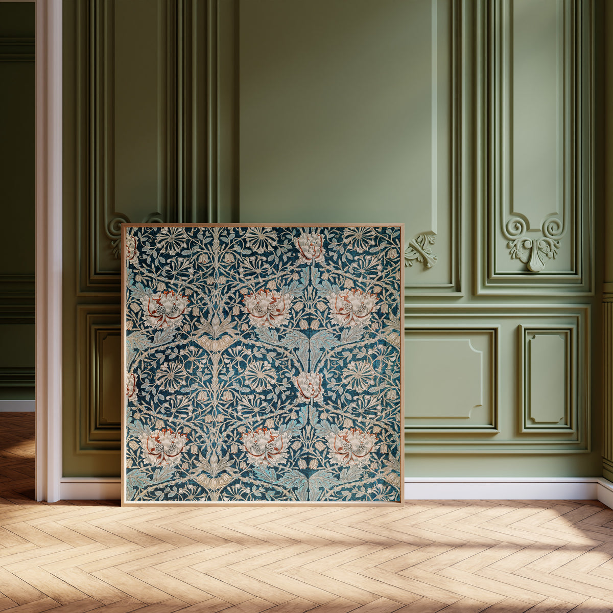Framed art print of Honeysuckle (Blue Linen) by William Morris, leaning against olive-green panelling on a herringbone floor