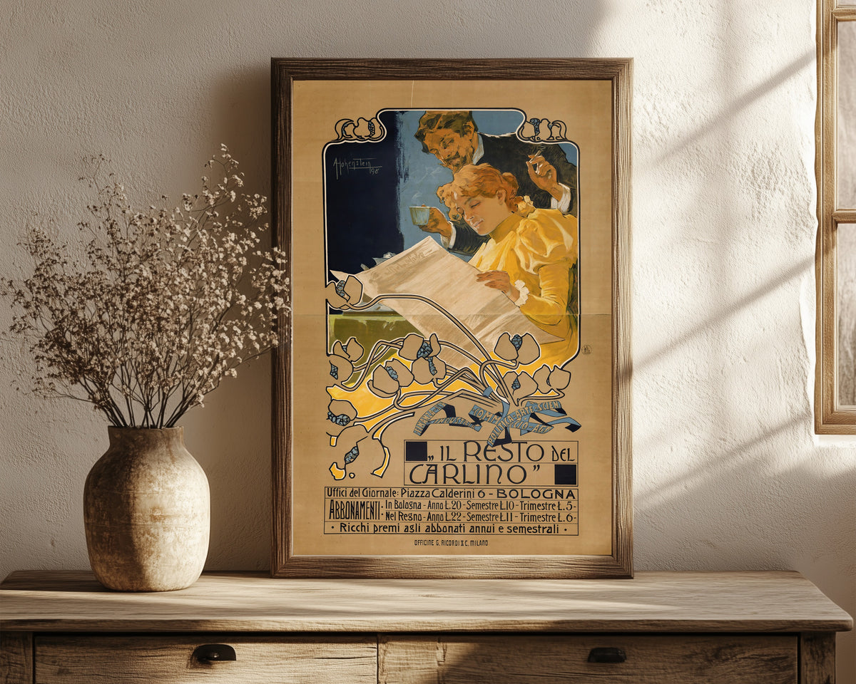 Framed art print of Il Resto del Carlino, Bologna by Adolfo Hohenstein, in a dark wood frame leaning on a rustic console beside dried flowers