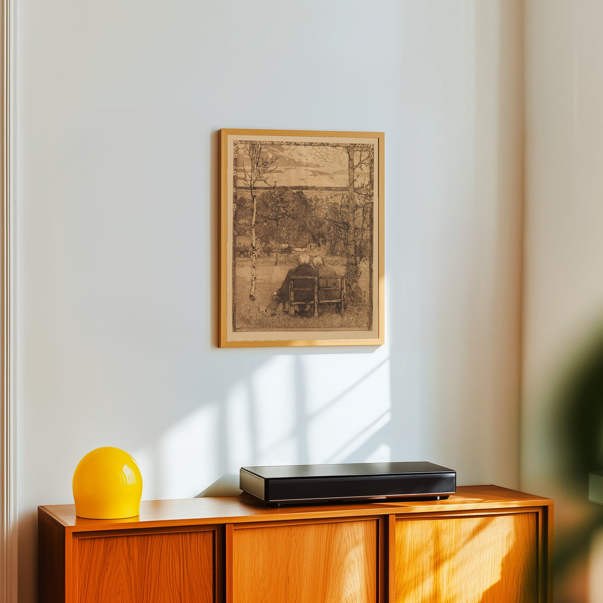 Framed art print of Im Mai by Heinrich Vogeler, in a light wood frame on a white wall above an orange sideboard
