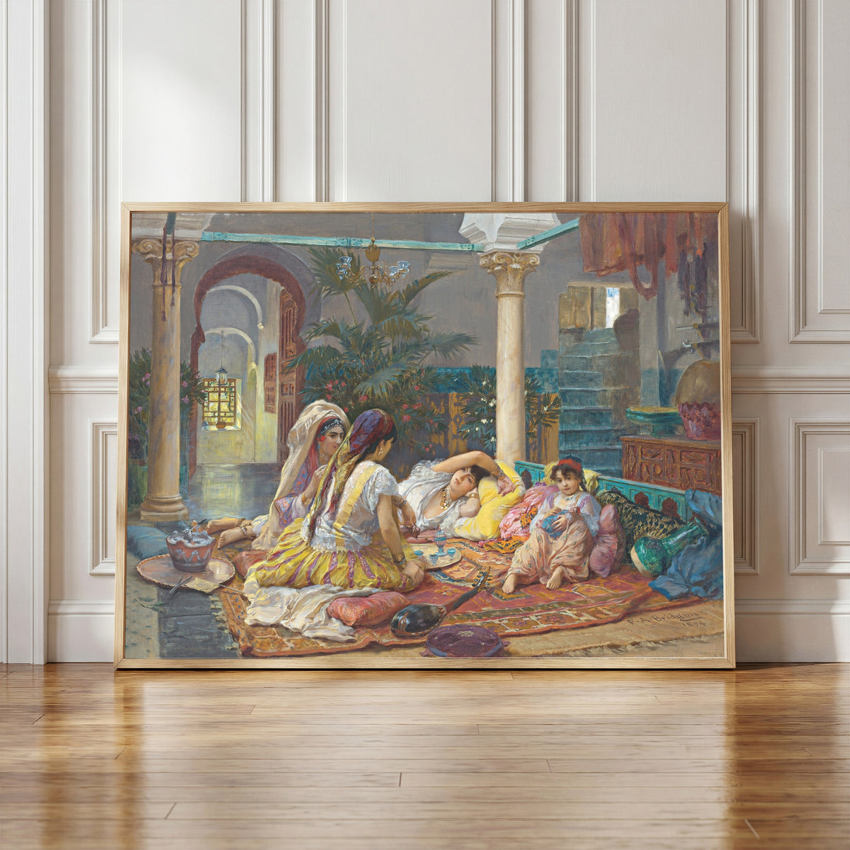 Framed art print of In the Harem by Frederick Arthur Bridgman, in a light wood frame leaning against a panelled white wall