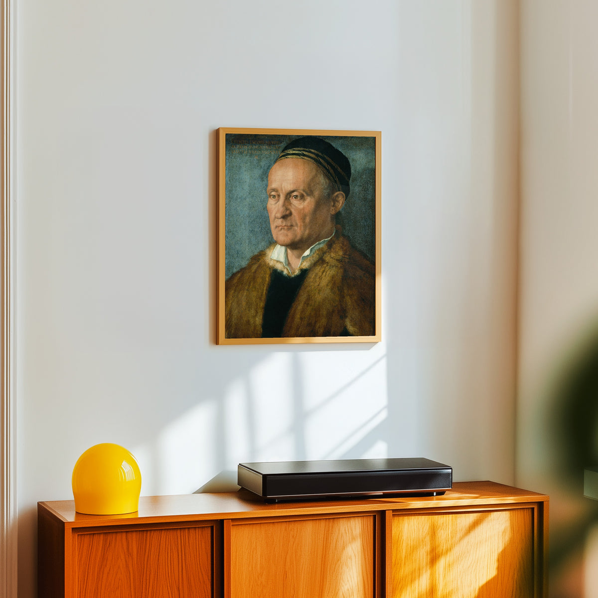 Framed art print of Jakob Muffel by Albrecht Dürer, in a light wood frame on a white wall above an orange sideboard
