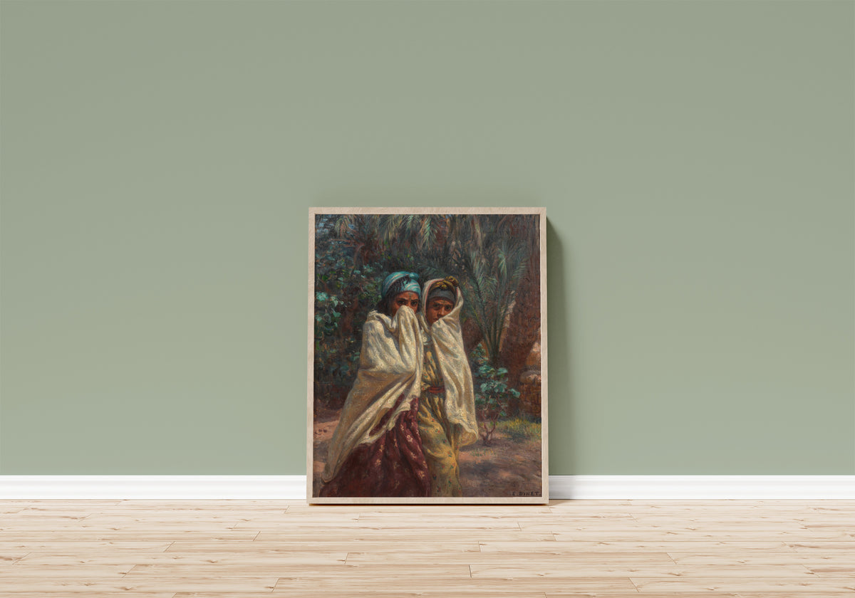 Framed art print of Jeunes filles revenant de la fête, claire de lune by Étienne Dinet, in a light wood frame leaning on a sage green wall above a wooden floor