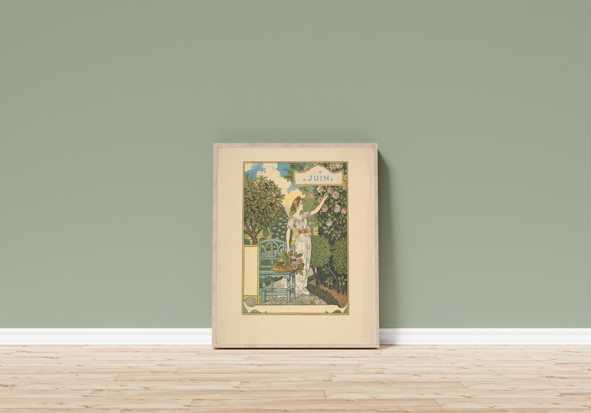 Framed art print of Juin by Eugène Grasset, in a light wood frame leaning on a sage green wall above a wooden floor