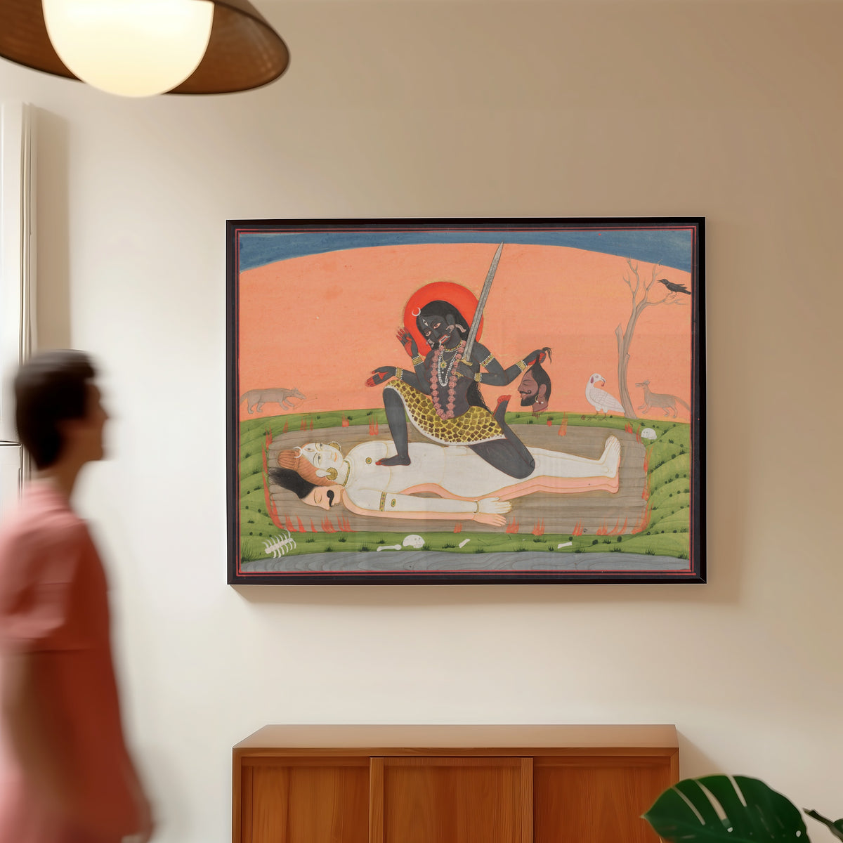 Framed art print of Kali on Shiva by Pahari school, in a slim black frame on a warm wall in a sunlit room