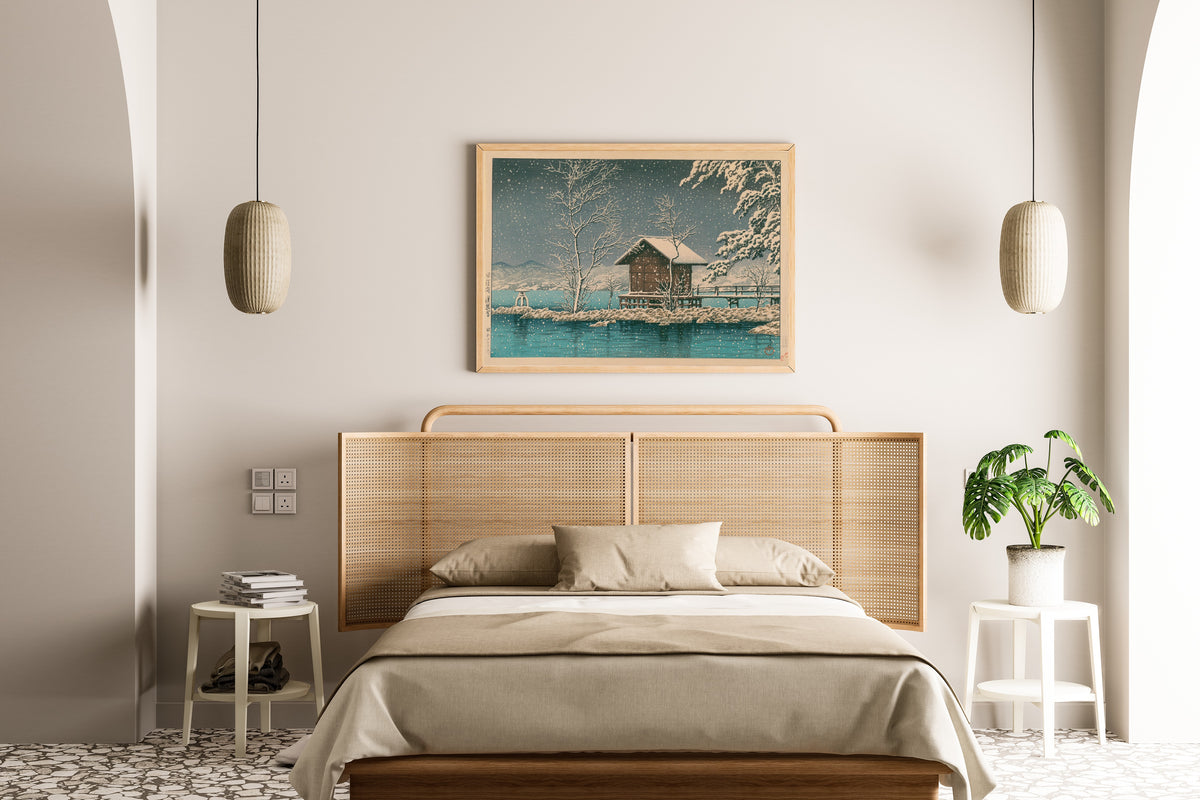 Framed art print of Kansanomiya Shrine at Lake Tazawa by Kawase Hasui, above a cane-headboard bed