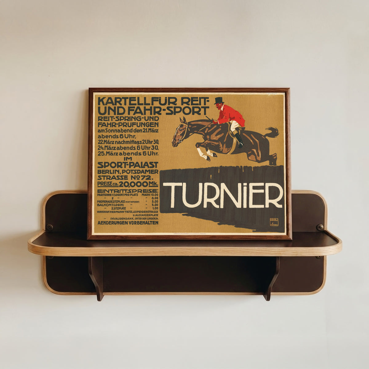 Framed art print of Kartell für Reit- und Fahr-Sport: Turnier by Ludwig Hohlwein, in a dark wood frame resting on a wall shelf