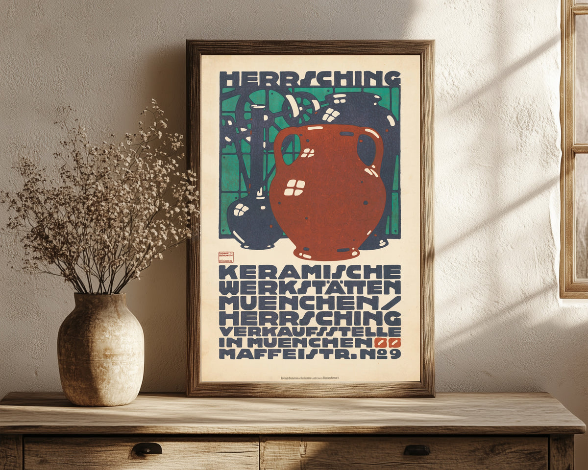 Framed art print of Keramische Werkstätten München: Herrsching by Ludwig Hohlwein, in a dark wood frame leaning on a rustic console beside dried flowers