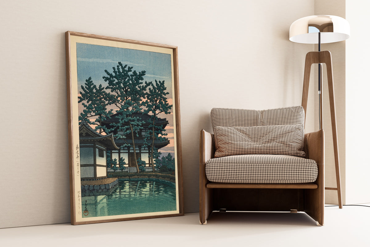 Framed art print of Kiko Temple, Nara Prefecture by Kawase Hasui, leaning against a wall beside an armchair and a floor lamp