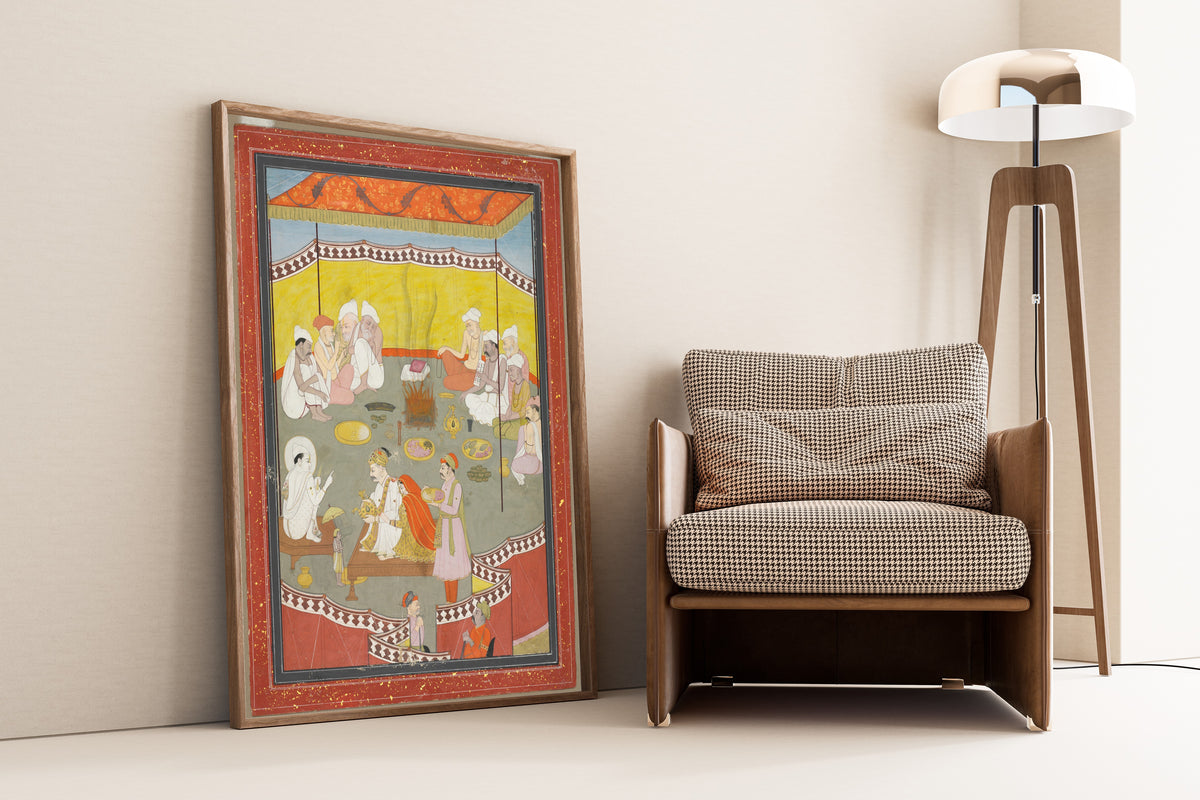 Framed art print of King Bali Gives a Gift of Land to Vamana by Pahari school, leaning against a wall beside an armchair and a floor lamp