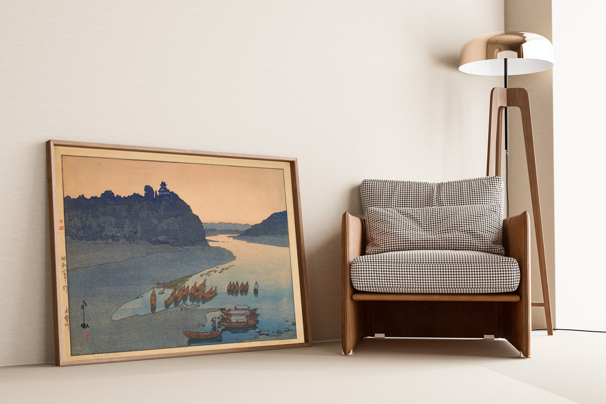 Framed art print of Kiso River by Hiroshi Yoshida, leaning against a wall beside an armchair and a floor lamp
