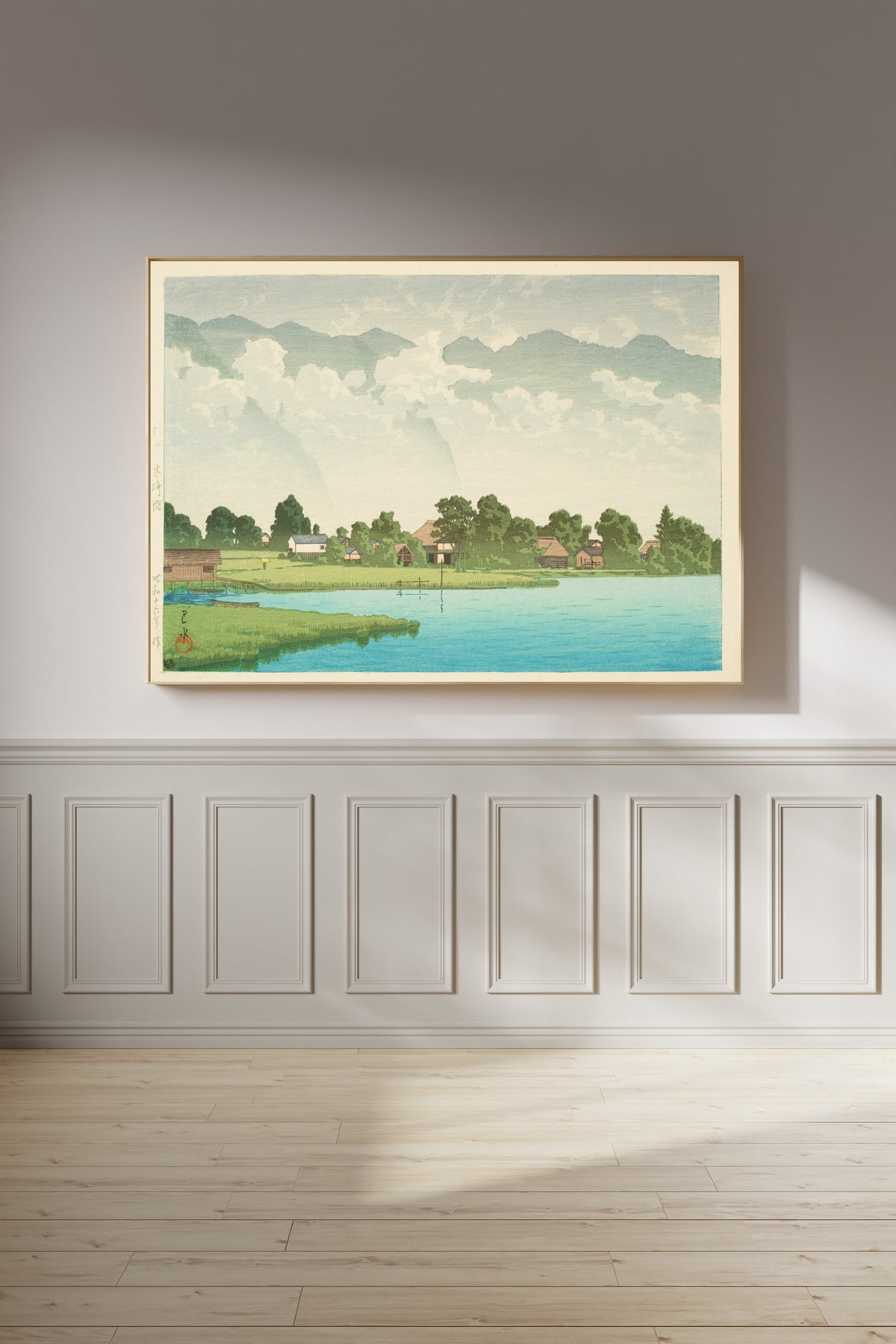 Framed art print of Kizaki Lake in Shinshu by Kawase Hasui, on a panelled wall in afternoon light