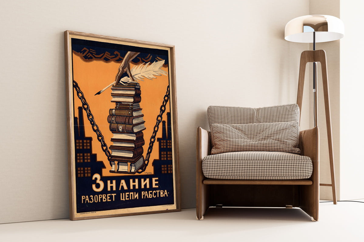 Framed art print of Knowledge Will Break the Chains of Slavery by Aleksei Radakov, leaning against a wall beside an armchair and a floor lamp