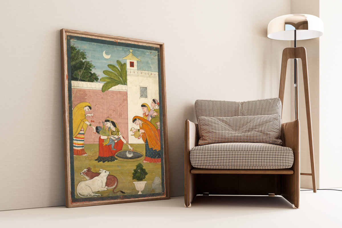 Framed art print of Krishna Reaching for the Moon by Pahari school, leaning against a wall beside an armchair and a floor lamp