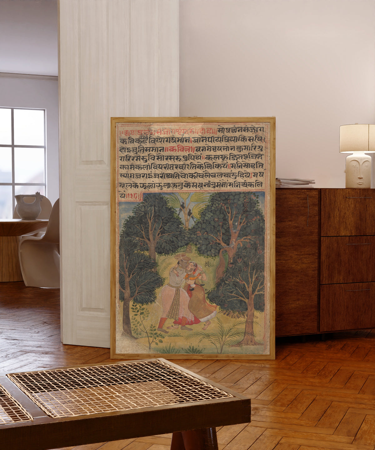 Framed art print of Krishna Woos Radha: Page from the Dispersed "Boston"… by Amber school, in a light wood frame leaning in a warm room with a parquet floor