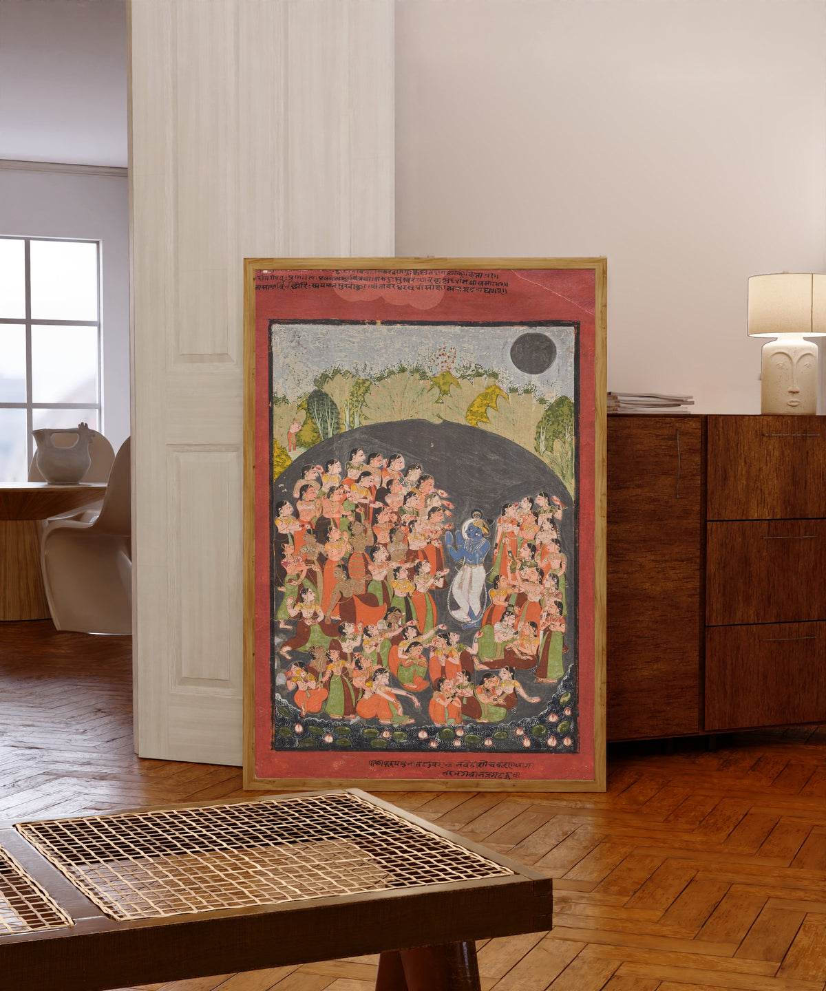 Framed art print of Krishna and the Gopis Gather for Rasamandala by Kota school, in a light wood frame leaning in a warm room with a parquet floor