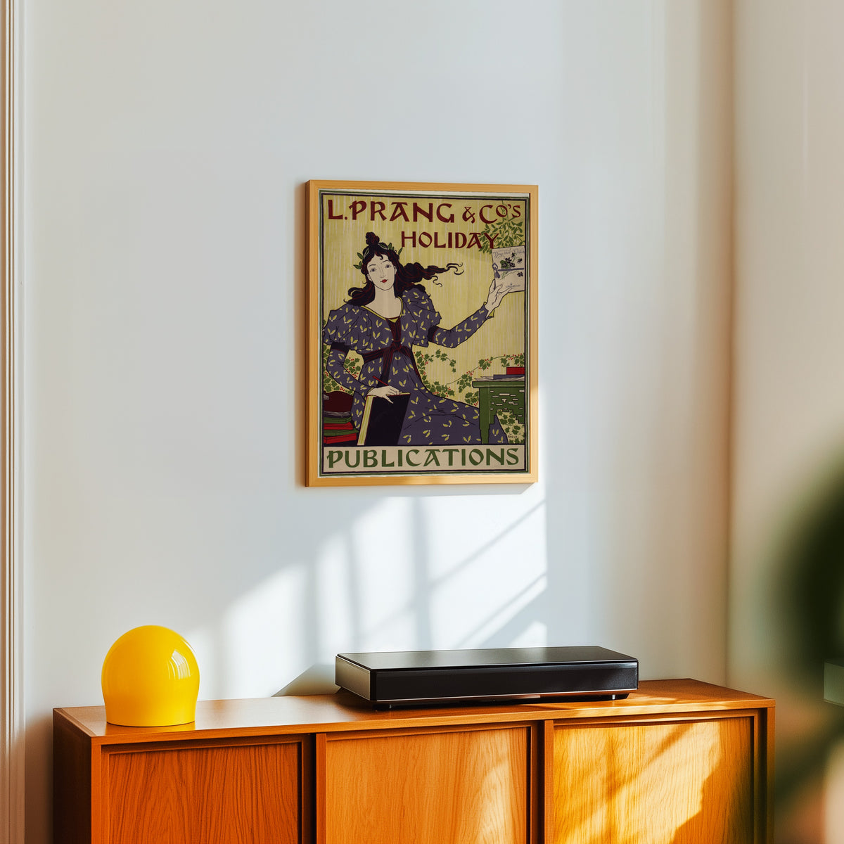 Framed art print of L. Prang & Co.'s Holiday Publications by Louis Rhead, in a light wood frame on a white wall above an orange sideboard
