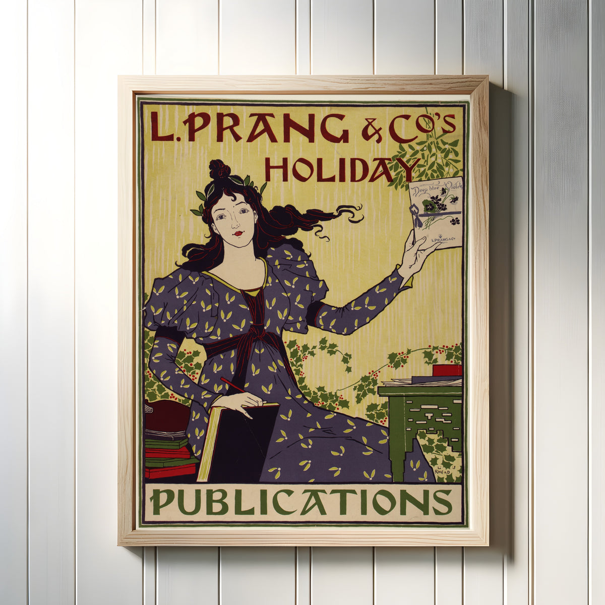 Framed art print of L. Prang & Co.'s Holiday Publications by Louis Rhead, in a light wood frame on a white panelled wall