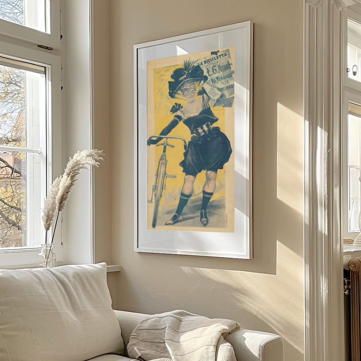 Framed art print of La Bicicletta by Aleardo Villa, in a sunlit living room above a sofa