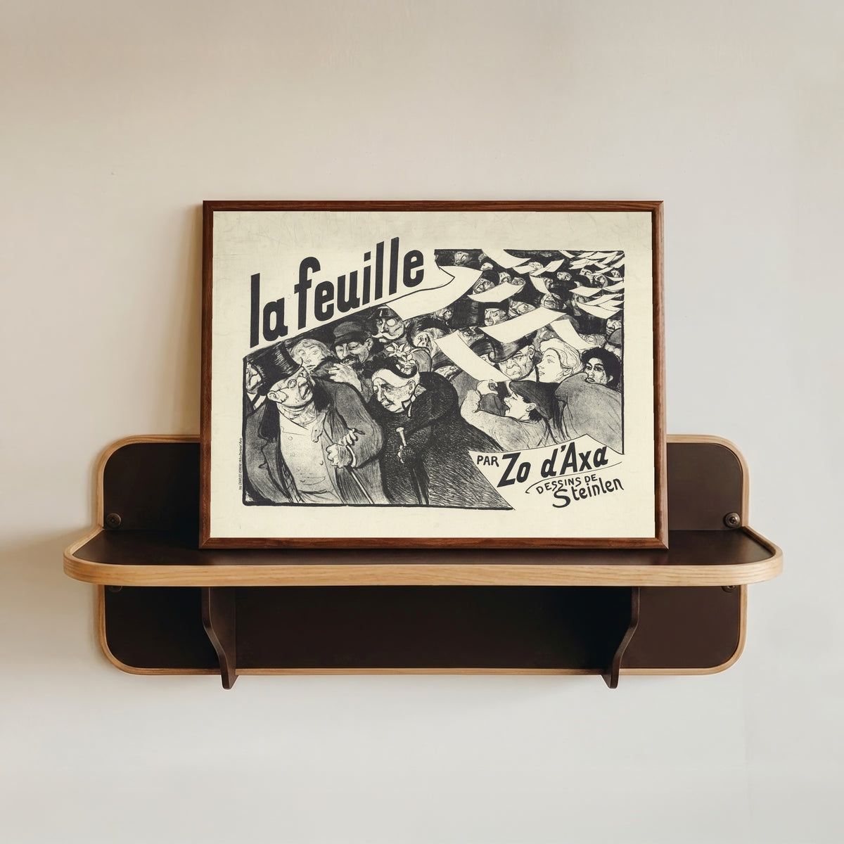 Framed art print of La Feuille, par Zo d’Axa, dessins de Steinlen by Théophile Steinlen, in a dark wood frame resting on a wall shelf